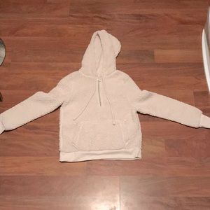 A cream colored hoodie with a zipper